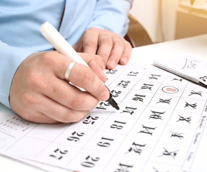 eine Hand streicht mit Stift auf einem Kalender ein Datum durch